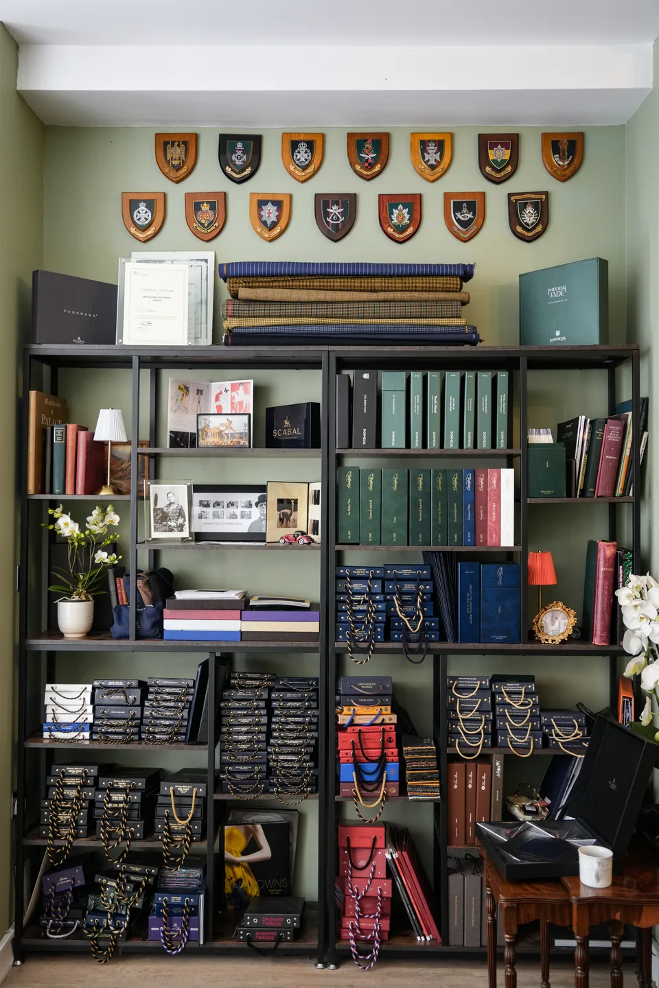 Shelves of cloth books displayed beneath a collection of regimental plaques.