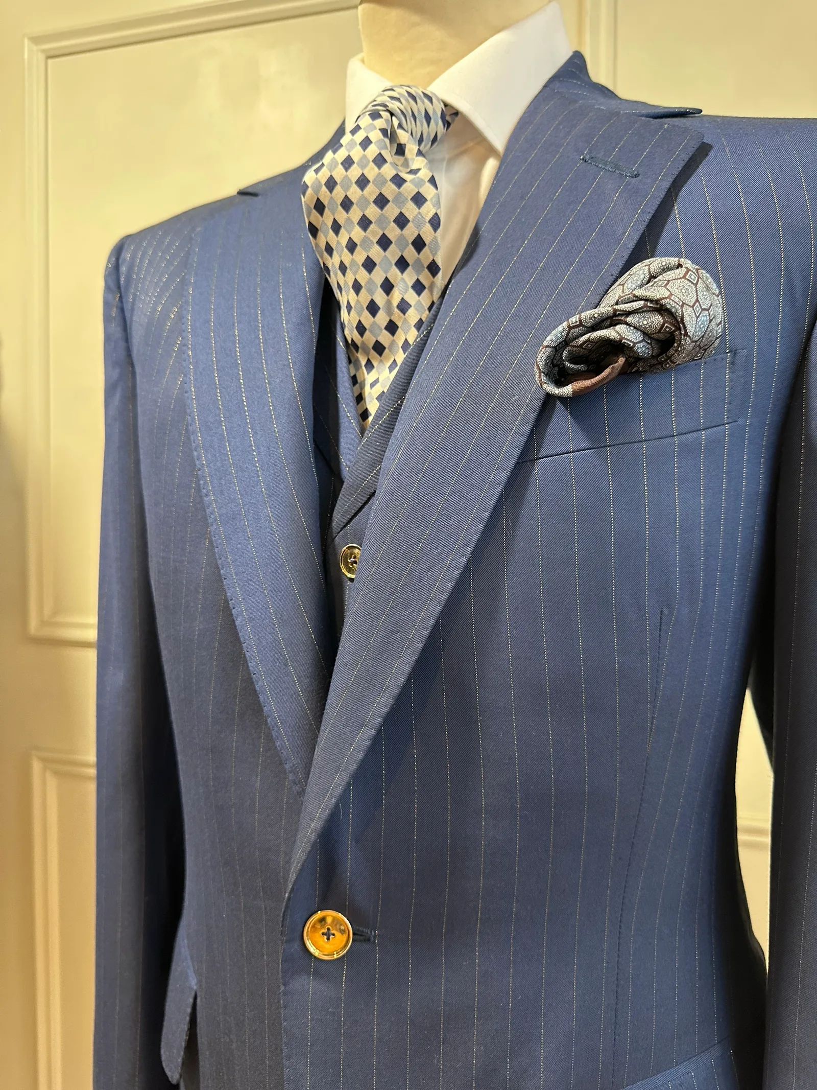 Upper-body view of the royal blue chalkstripe three-piece suit, highlighting fine pale chalkstripes, notch lapels and decorative gilt buttons.