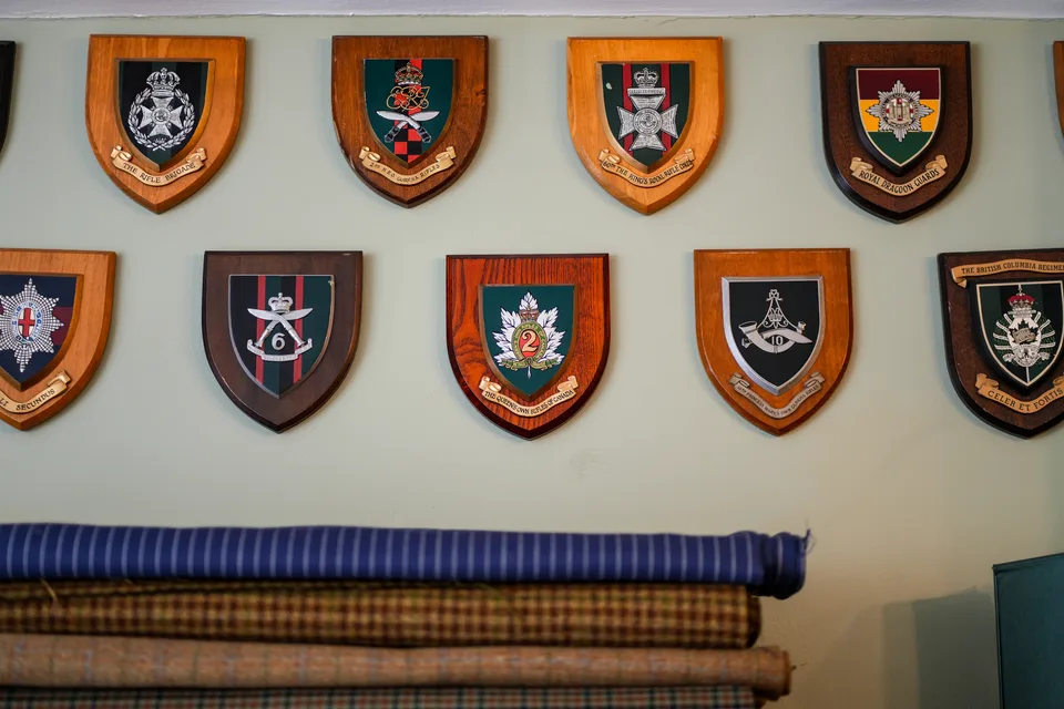 Military presentation shields displayed above rolls of checked and striped cloth