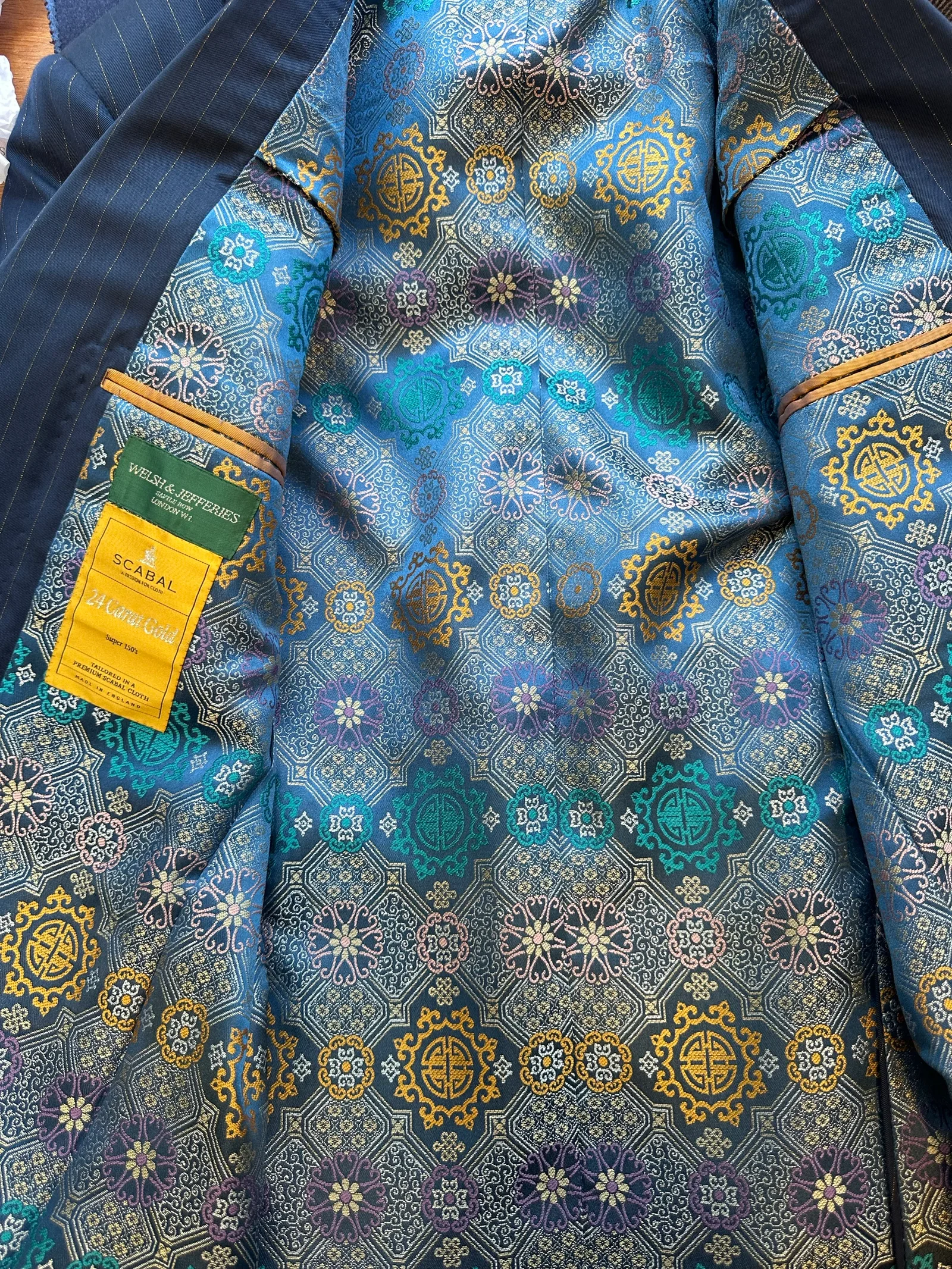 Interior view of the royal blue chalkstripe three-piece suit, revealing a jewel-toned blue, turquoise and gold medallion lining.