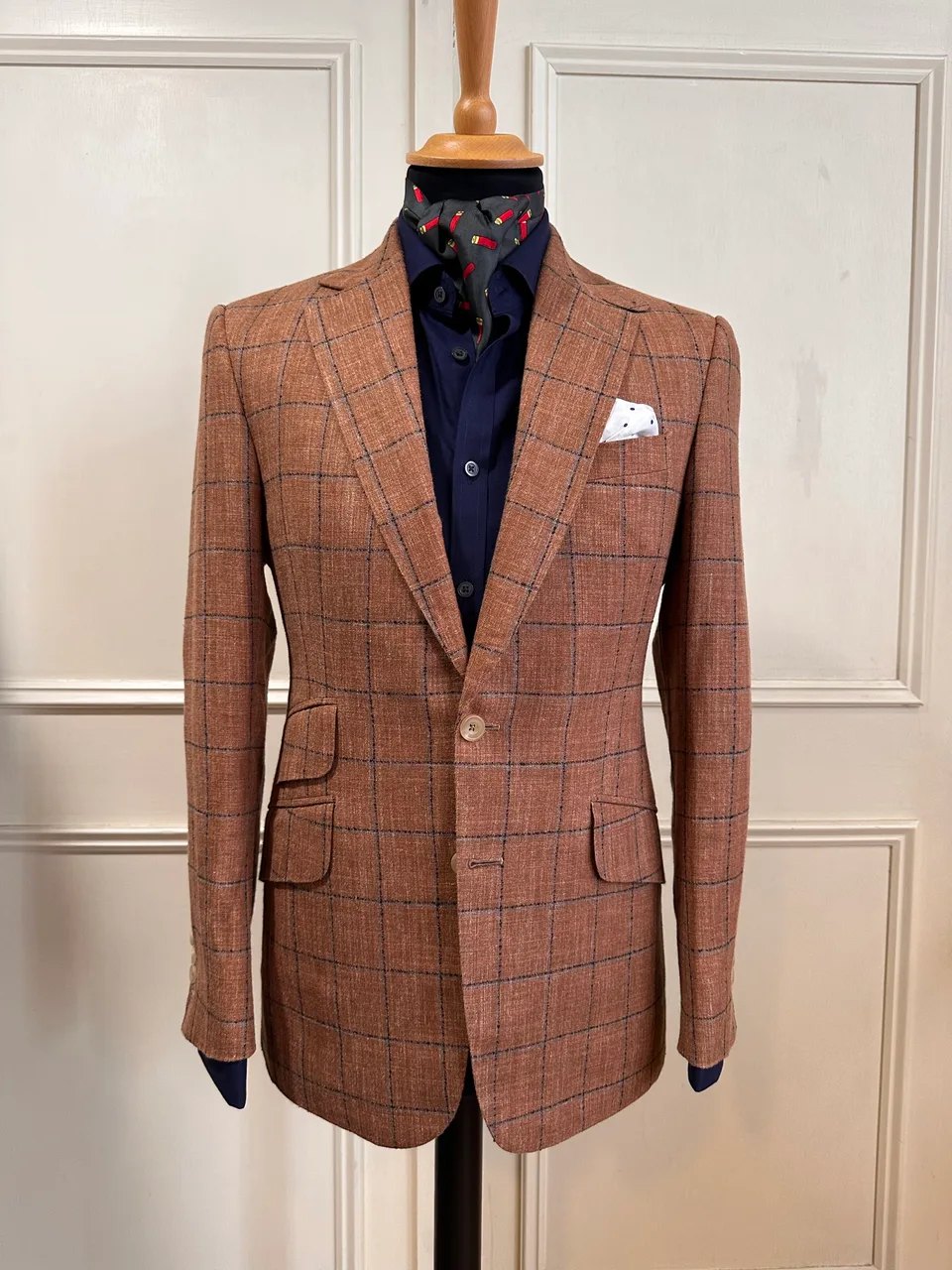 Front mannequin view of a rust windowpane sport coat, showing navy windowpane, notch lapels, stacked hip pockets and pale horn buttons.