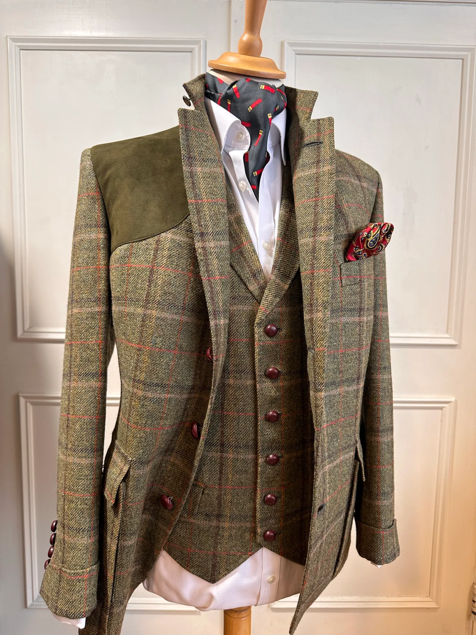 Front mannequin view of the olive windowpane country three-piece suit, tailored with red windowpane checks, dark suede shoulder panels and country detailing.