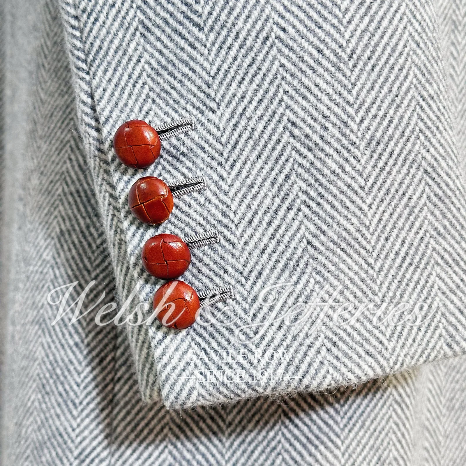 Cuff and button detail of the pale-grey herringbone cape overcoat.