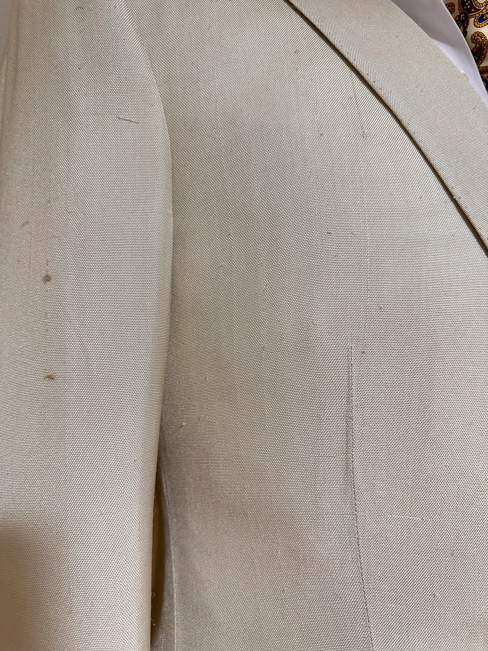 Close view of the ivory summer suit’s shoulder, notch lapel and softly slubbed cloth.