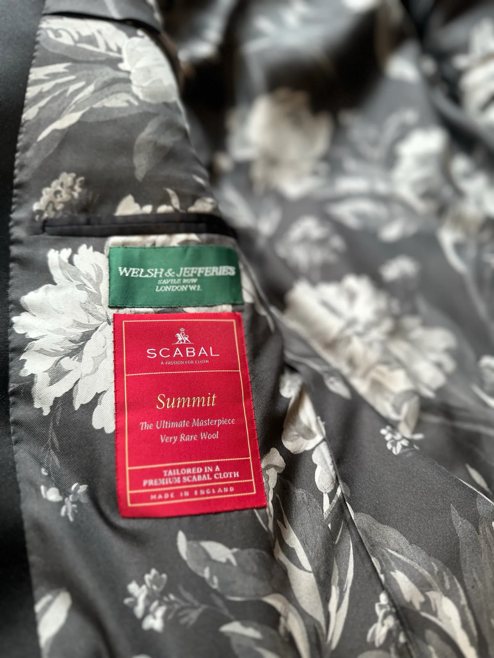 Interior view of the black satin peak-lapel tuxedo, revealing a monochrome black-and-silver floral lining.