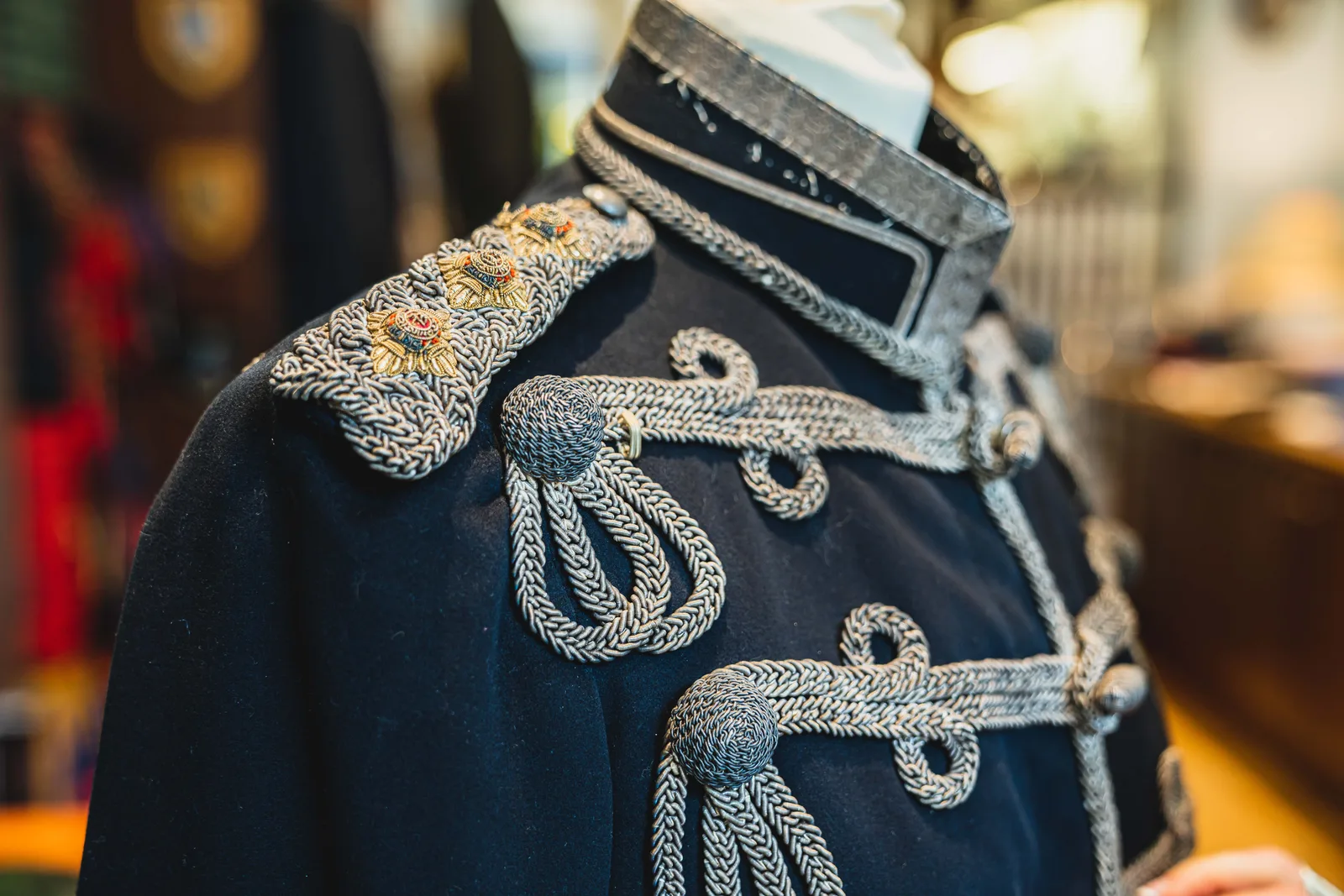 Silver frogging and embroidered shoulder insignia define a dark cavalry tunic.