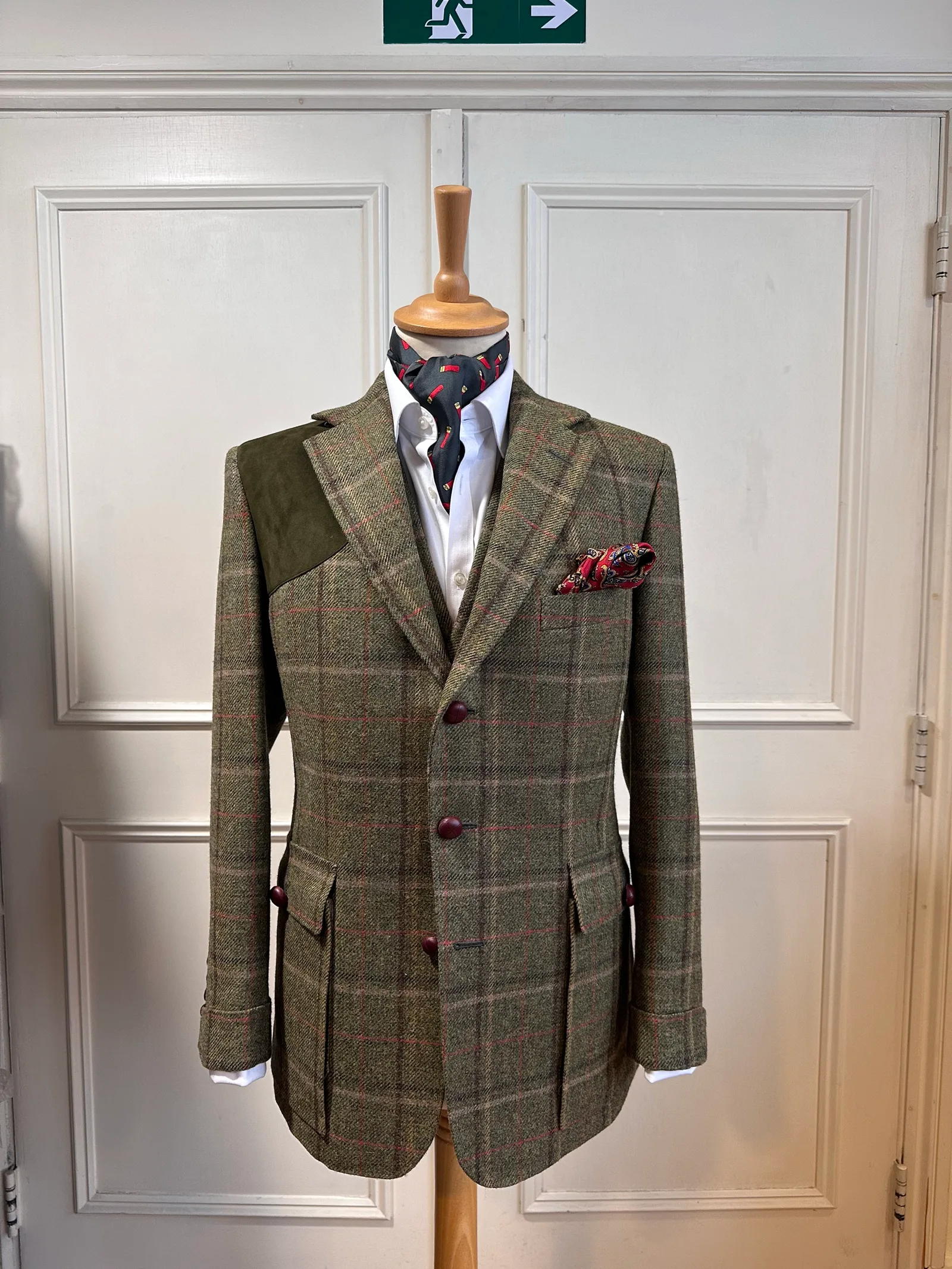 Front mannequin view of the olive windowpane country three-piece suit, tailored with red windowpane checks, dark suede shoulder panels and country detailing.