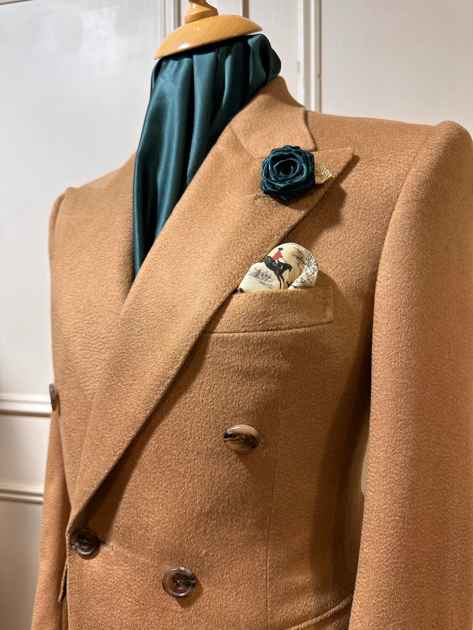 Close view of the camel vicuña overcoat’s sweeping peak lapel and dark horn buttons.