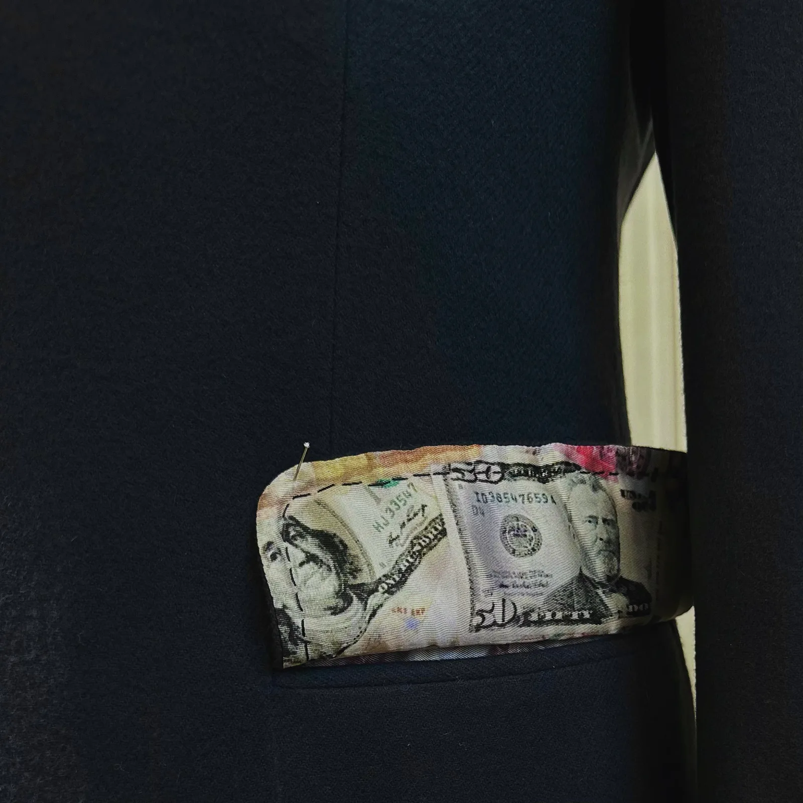 The cuff of a navy vicuña jacket opens to reveal a banknote-print silk lining.