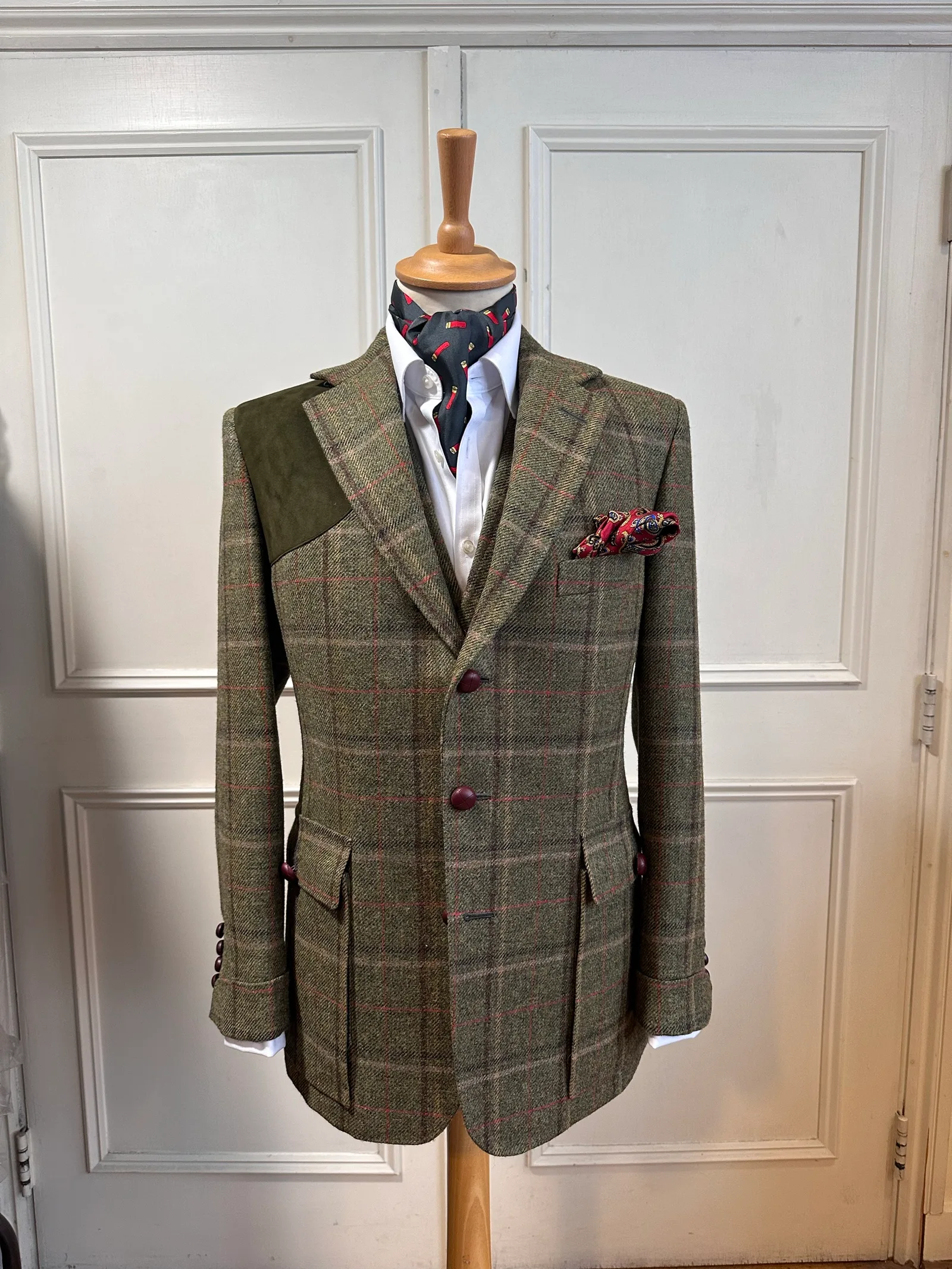 Front mannequin view of the olive windowpane country three-piece suit, tailored with red windowpane checks, dark suede shoulder panels and country detailing.