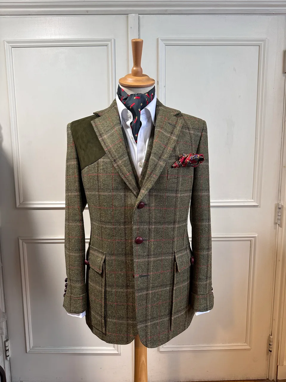 Front mannequin view of the olive windowpane country three-piece suit, tailored with red windowpane checks, dark suede shoulder panels and country detailing.
