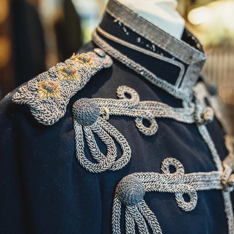Silver bullion frogging, olivets, corded collar and embroidered shoulder devices on dark hussar cloth.