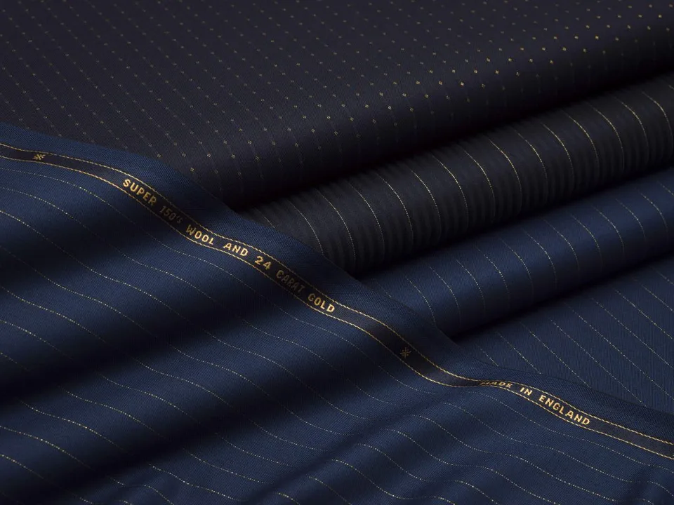 成匹的午夜蓝 Scabal 面料,金色细条纹与织边商标可见。