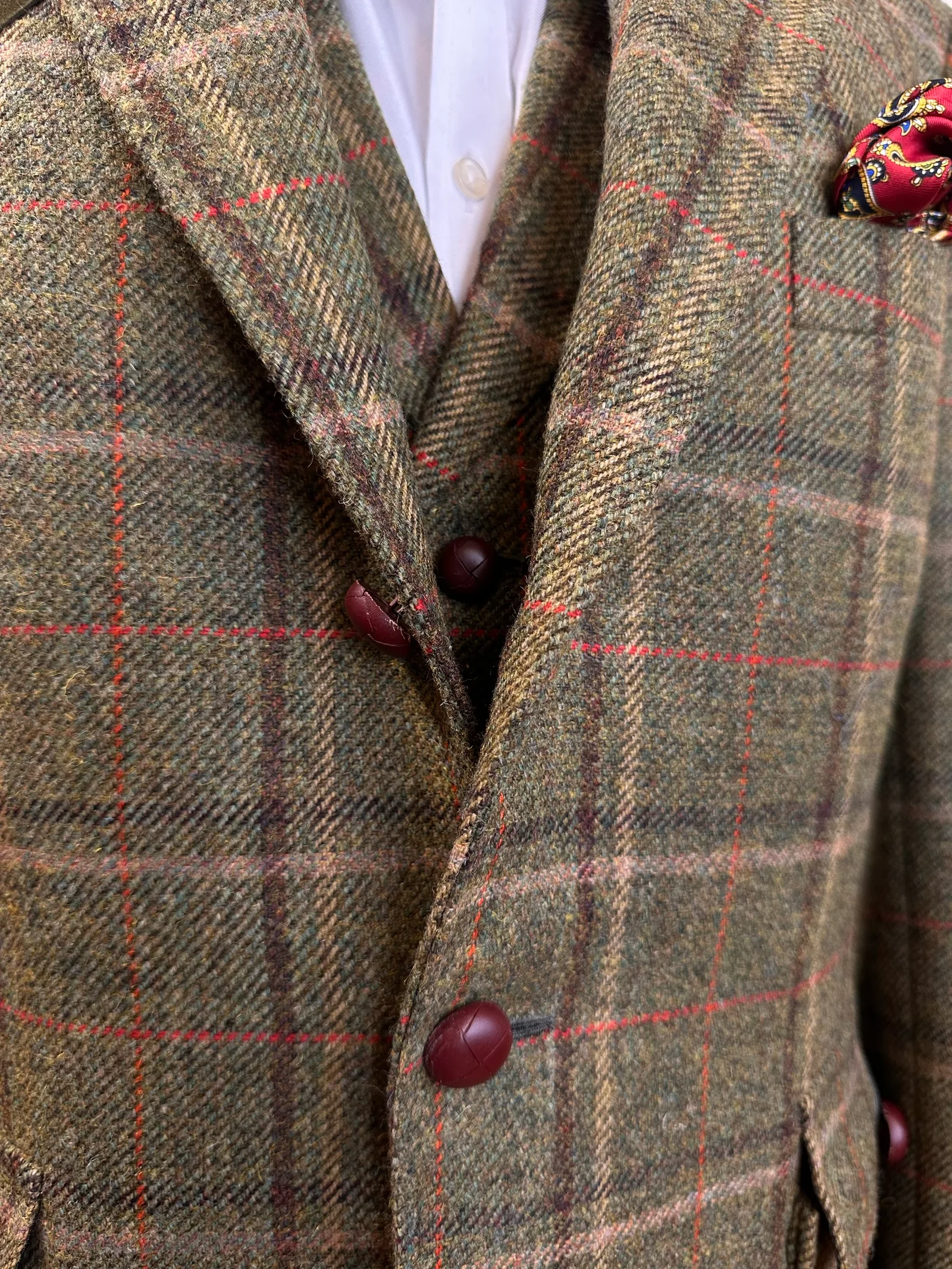 Upper-body view of the olive windowpane country three-piece suit, highlighting red windowpane checks, dark suede shoulder panels and country detailing.