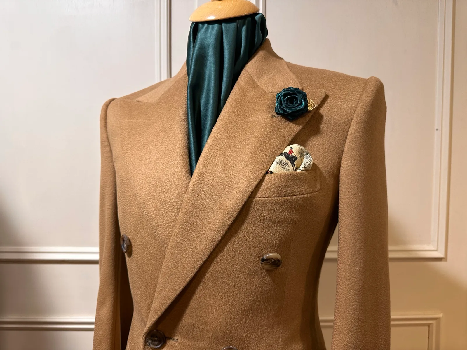 Close view of the camel vicuña overcoat’s sweeping peak lapel and dark horn buttons.