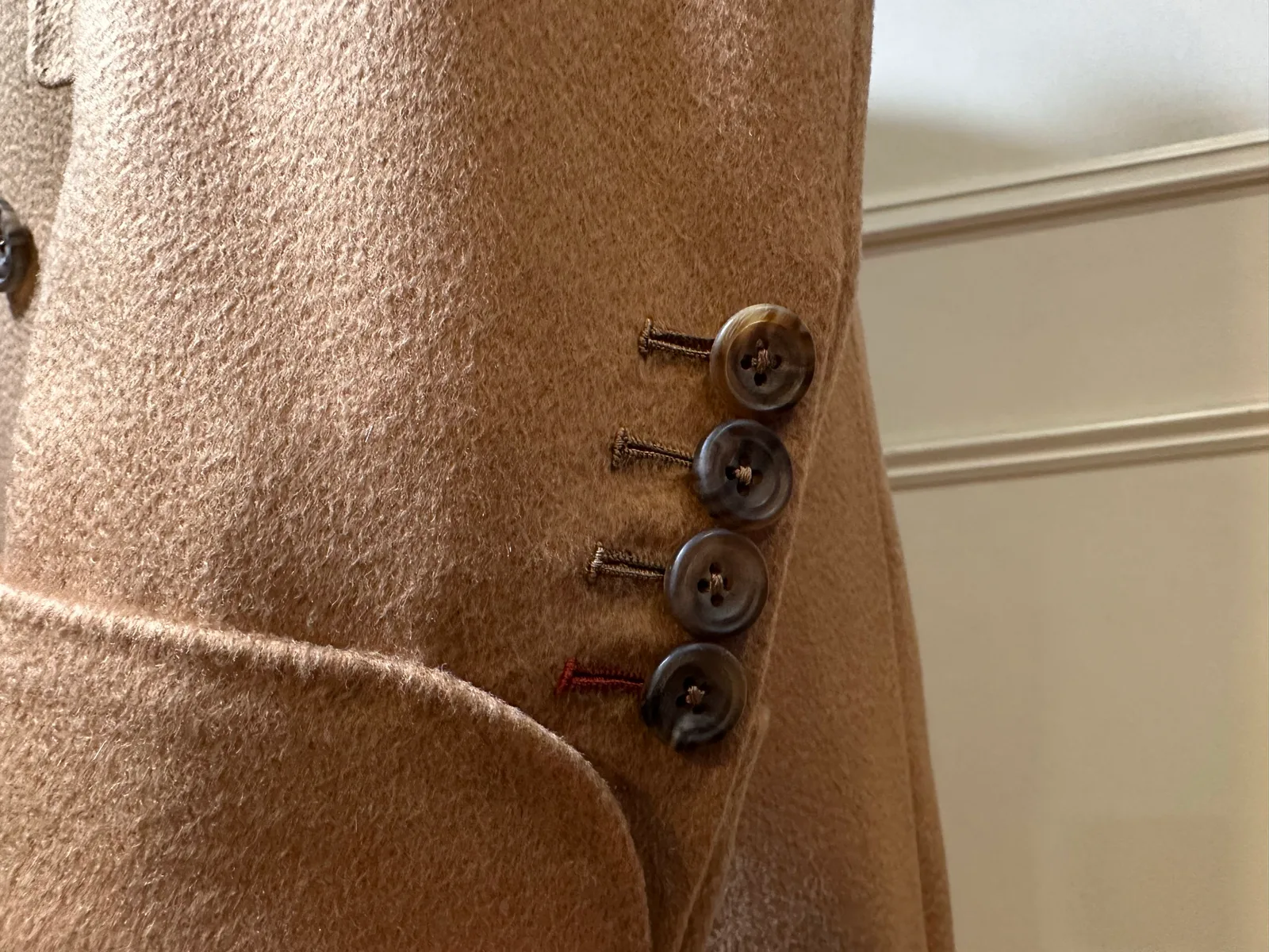 Close view of the camel vicuña overcoat’s turnback cuff and four dark horn buttons.