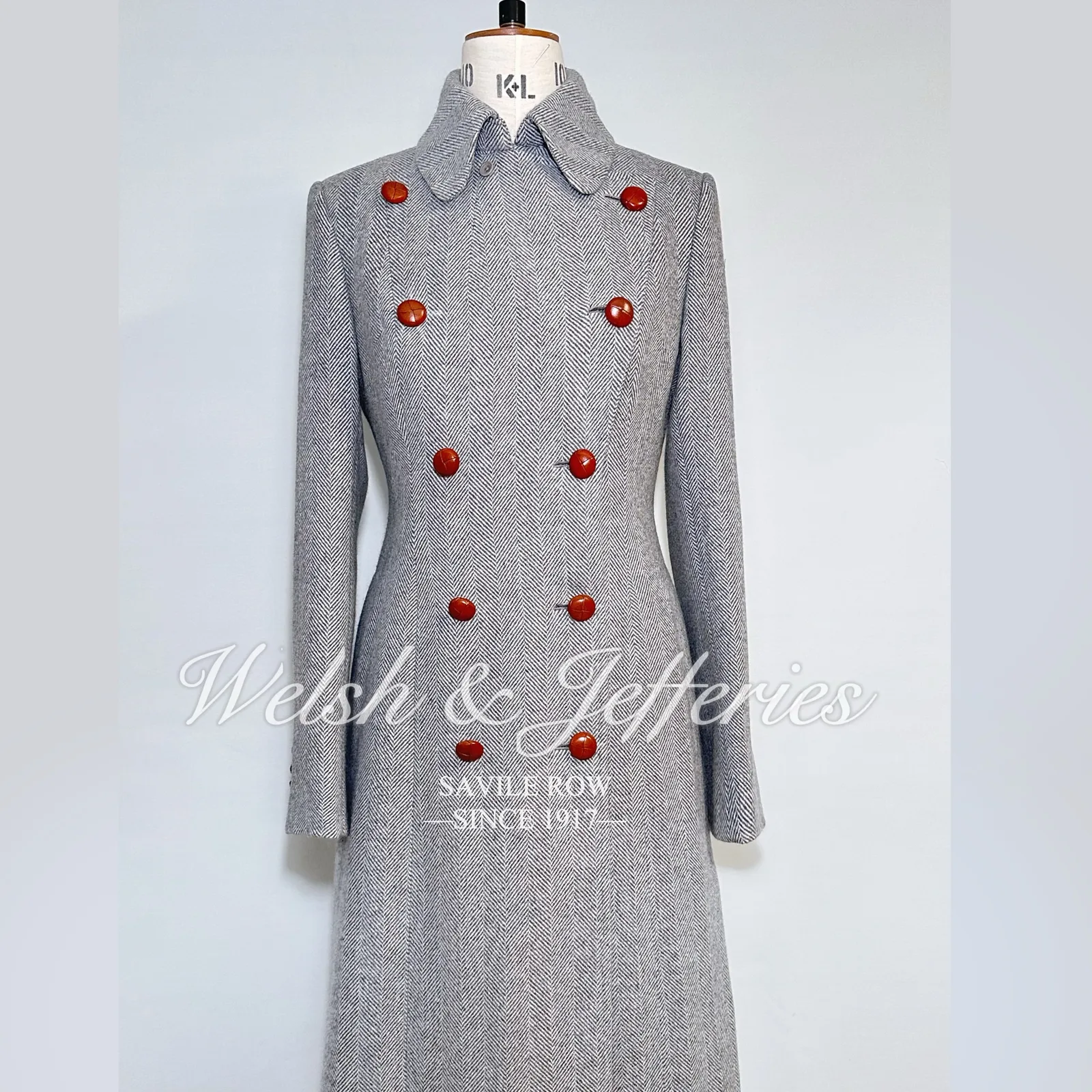 Alternate full view of the pale-grey herringbone cape overcoat.