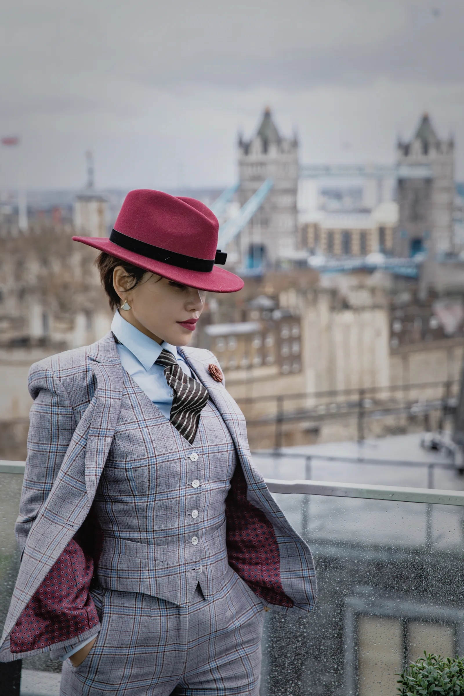 A woman wearing a grey Prince of Wales three-piece suit overlooking London.