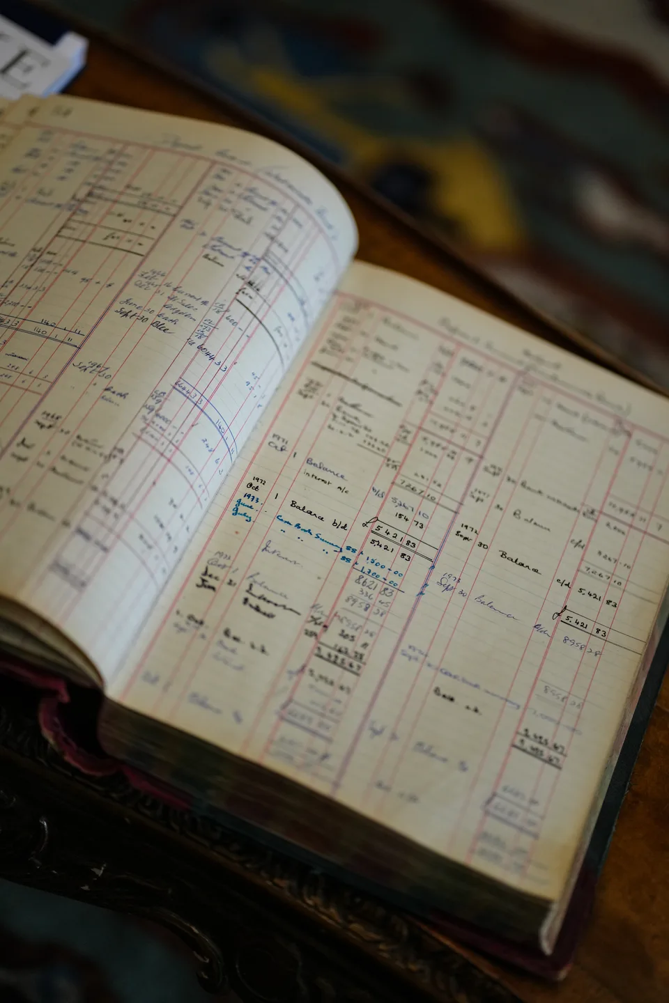 An open historic tailoring ledger reveals rows of handwritten client entries.