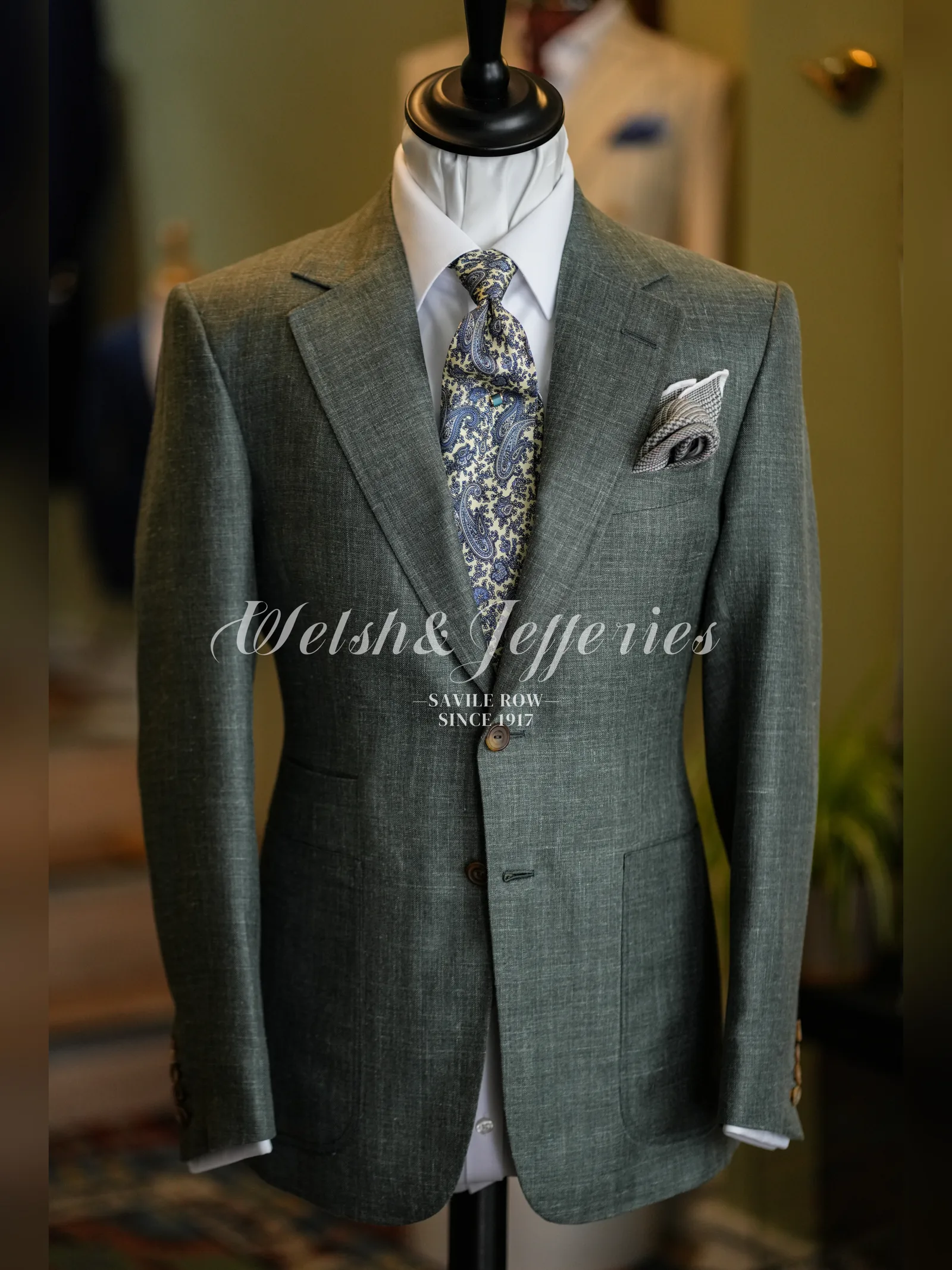 Full front view of a moss-grey crosshatch summer jacket on a tailor’s mannequin
